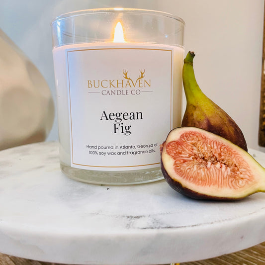 Lit Aegean Fig candle placed on top of marble stand with fresh figs.